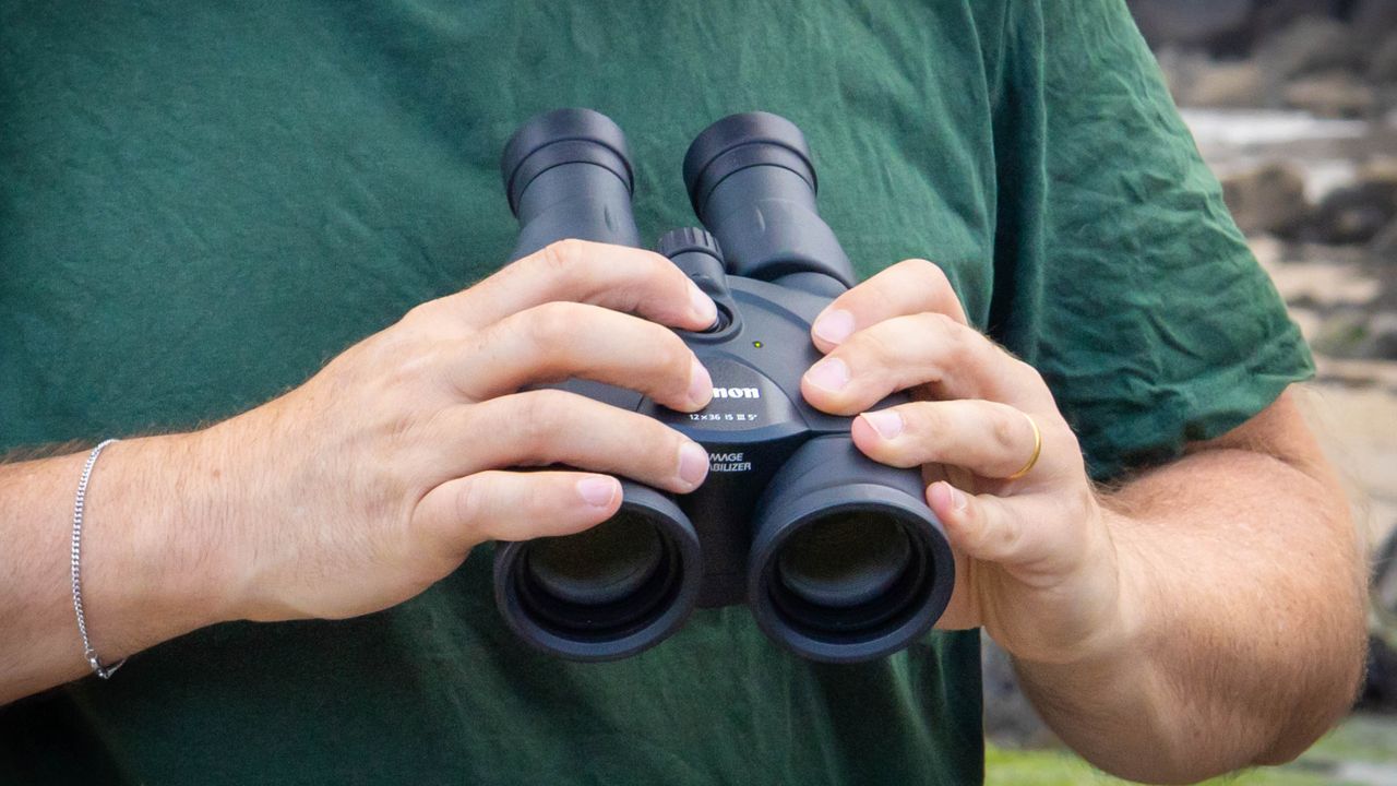 A close up of the IS button being pressed on the Canon 12z36 IS III binoculars.
