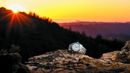 The Hamilton Khaki Field Expedition on a rock in front of a sunset