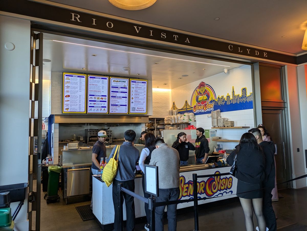 Photo of people lined up a burrito stand indoors shot by Pixel 8a