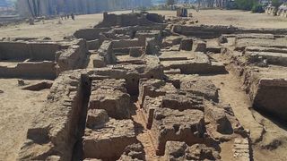 A photo showing the ruins of what once was a Roman residence in Luxor. There are sand-colored rock walls forming corridors and several rooms.