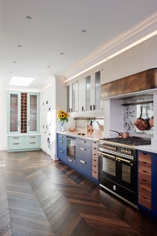 blue kitchen with white units and pale aqua cabinet, wooden floor, black range cooker, mirrored splash back