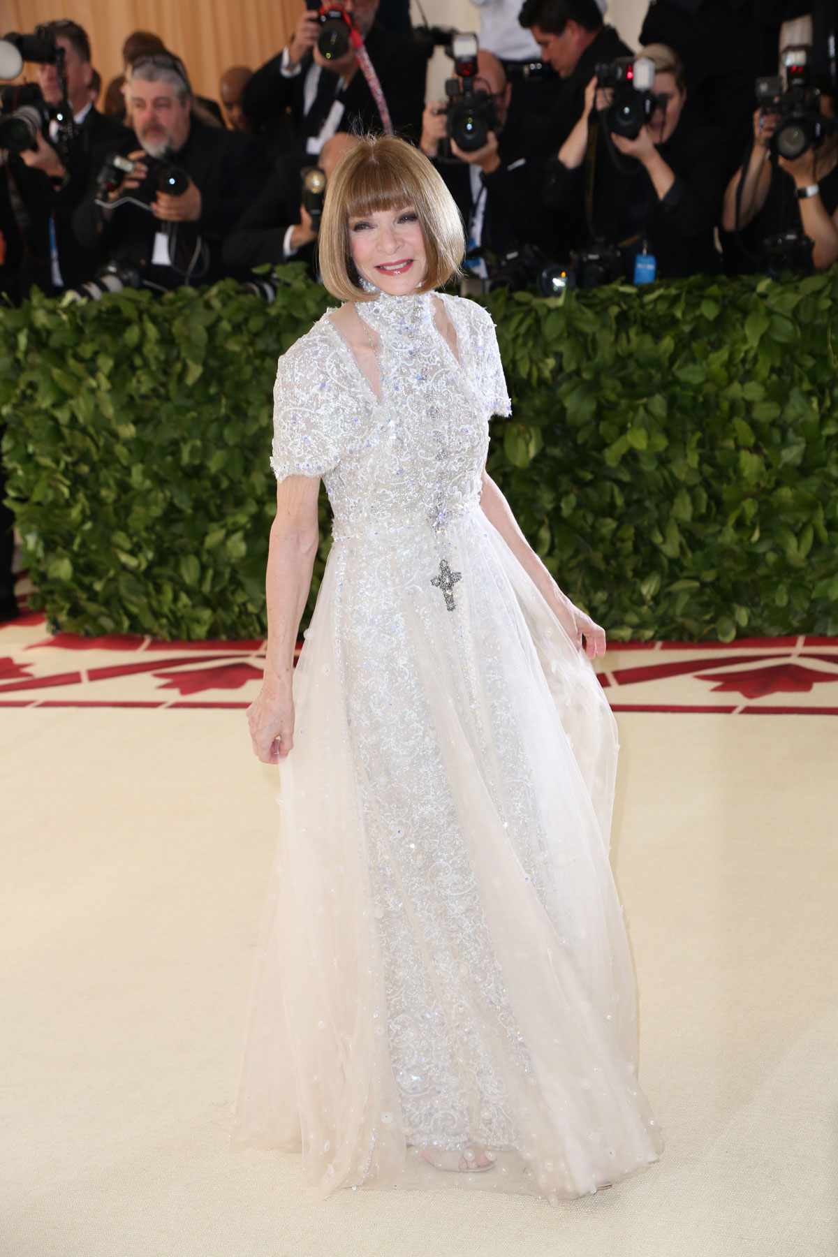 Anna Wintour wears a white beaded gown with a cross necklace.