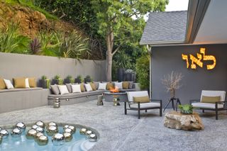 A plunge pool with a firepit and built-in seating outside