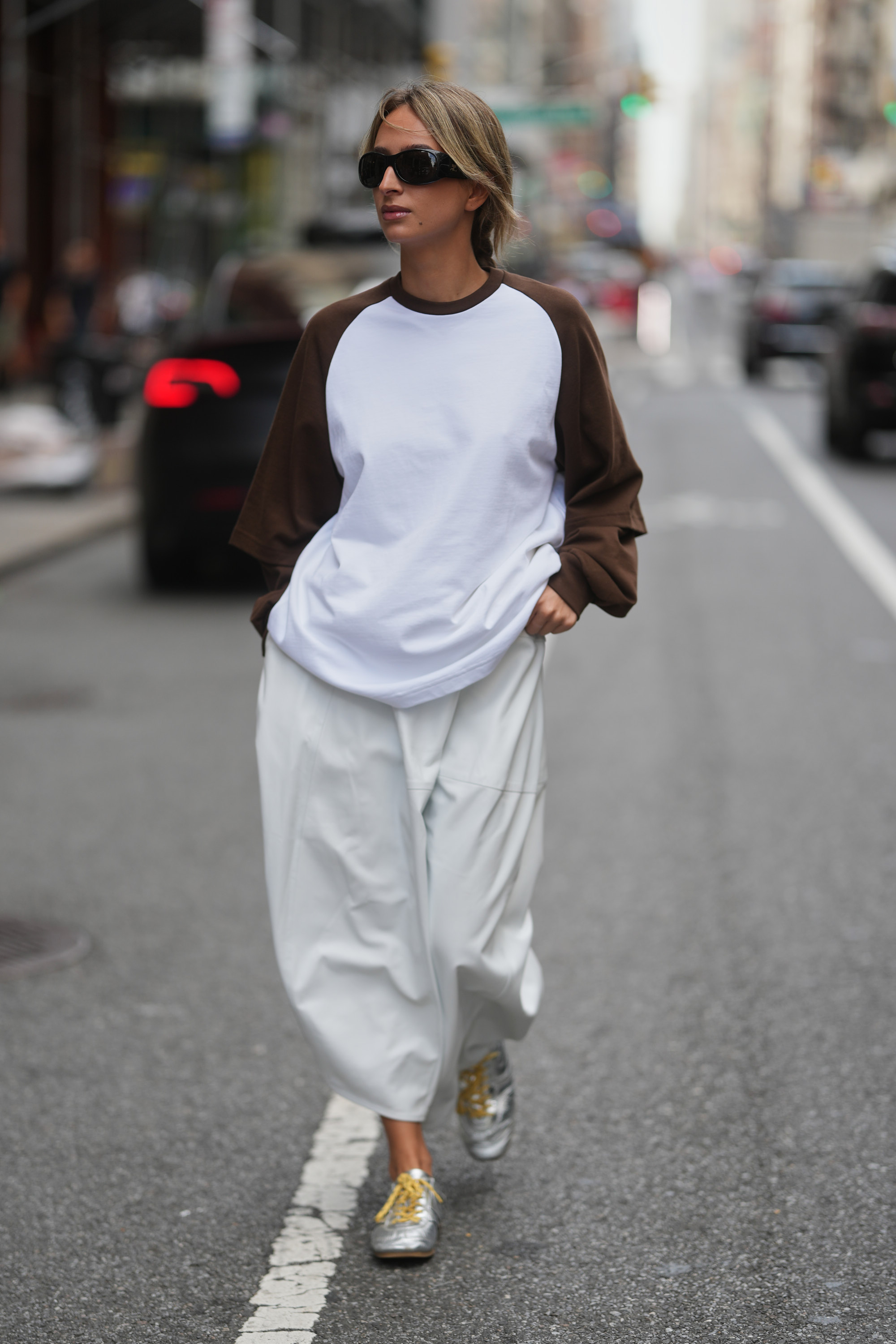 NEW YORK, NEW YORK - SEPTEMBER 13: Isabelle Allain is seen wearing black sunglasses, a Tibi oversized white t-shirt with brown sleeves, white pants and Dries Van Noten silver sneakers on September 13, 2025 in New York City. (Photo by 305pics/GC Images)