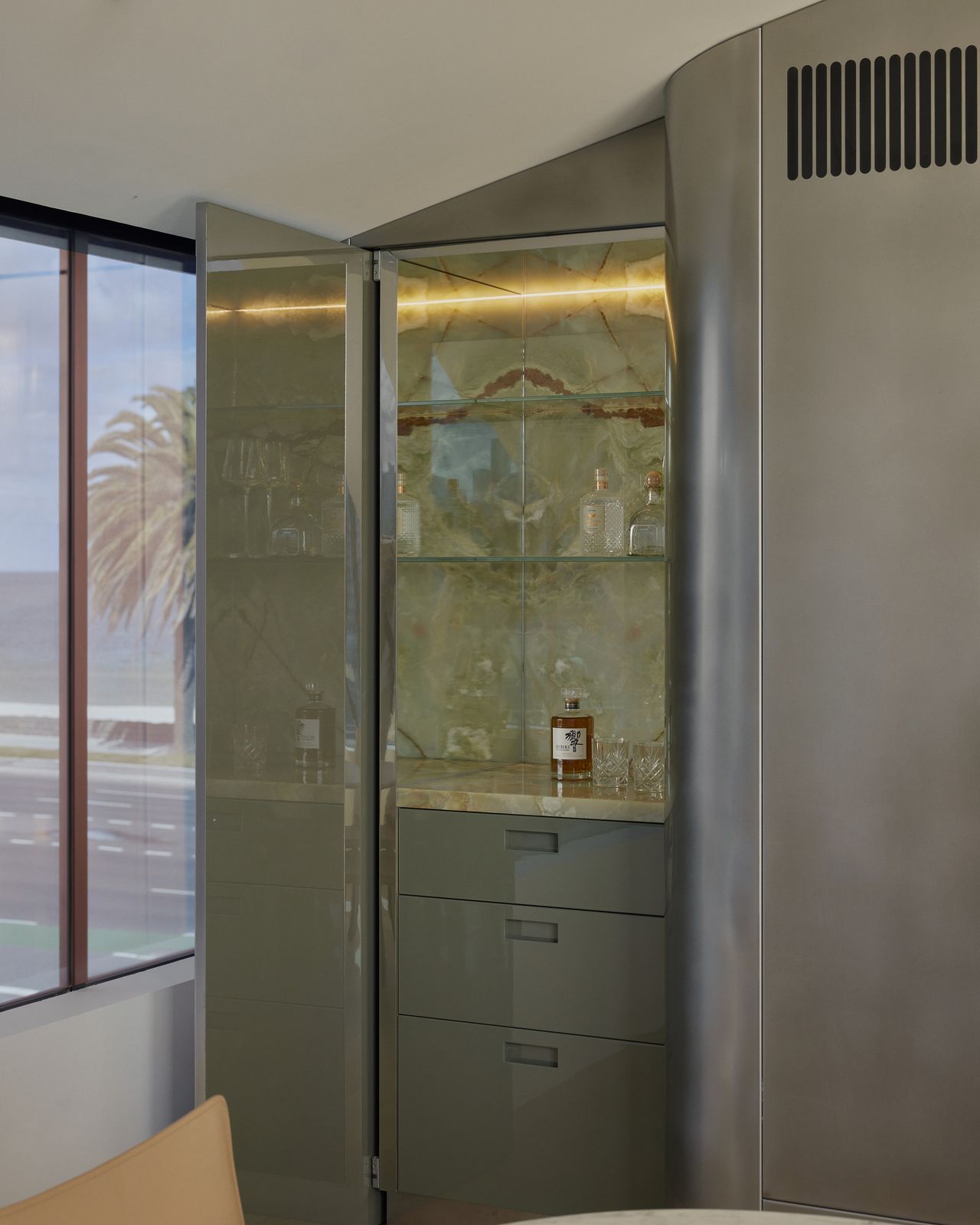 green home bar with onyx backsplash and stainless steel joinery