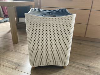 Mila Air Purifier pictured on wooden floor beside TV cabinet