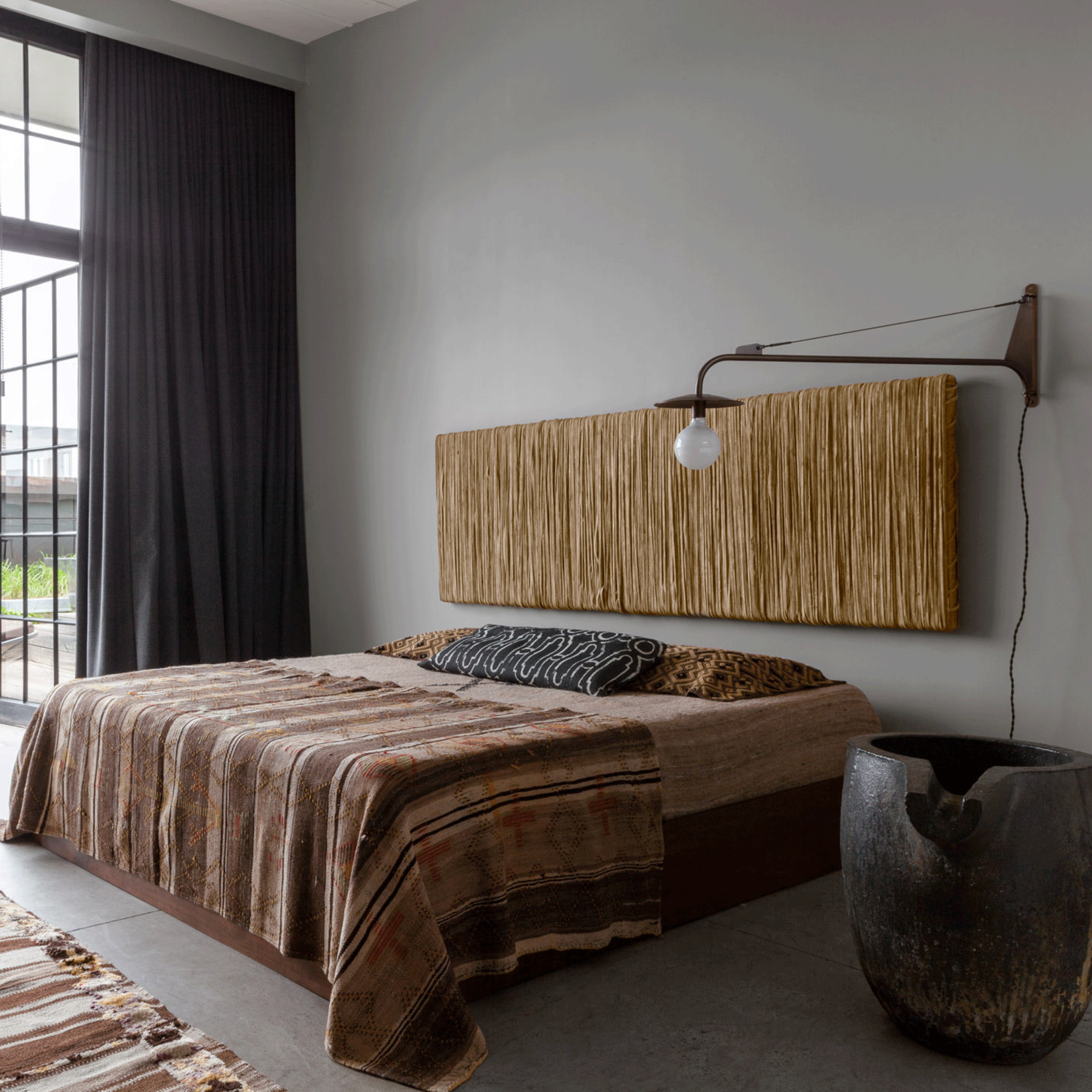 Grey bedroom with a raffia headboard that also acts as a piece of art