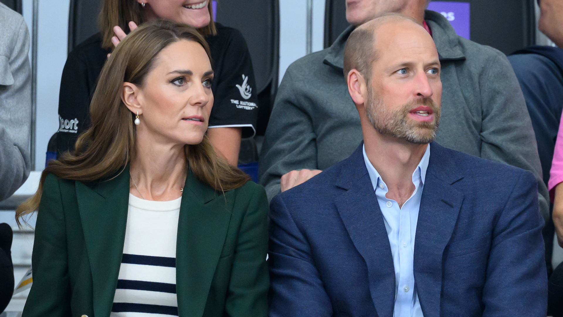 Princess Kate wears a green blazer a Breton striped top and Prince William has a bald head and wears a navy suit