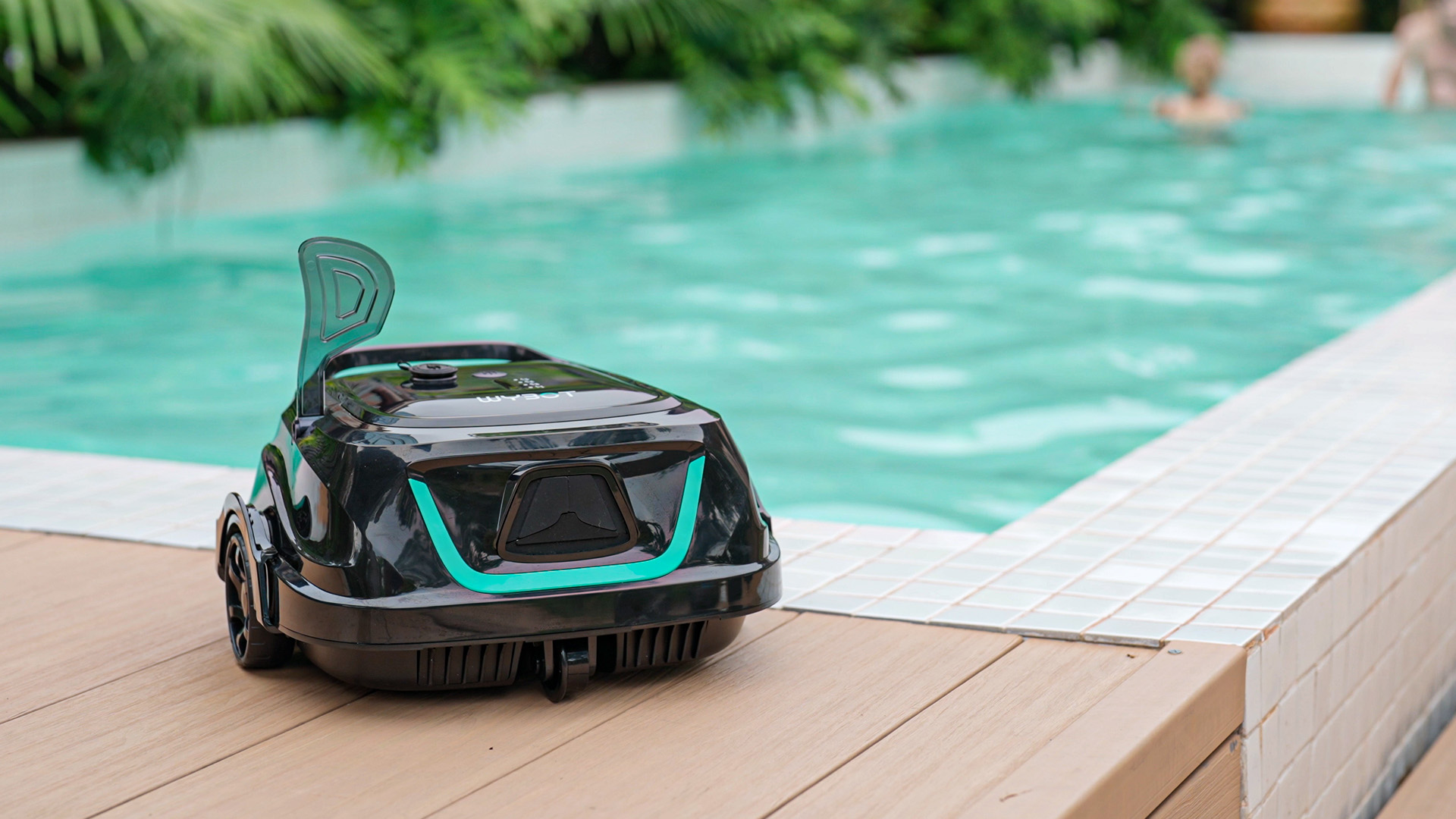 A WYBOT A1 robotic pool cleaner sits on a deck beside a mosaic tiled pool.