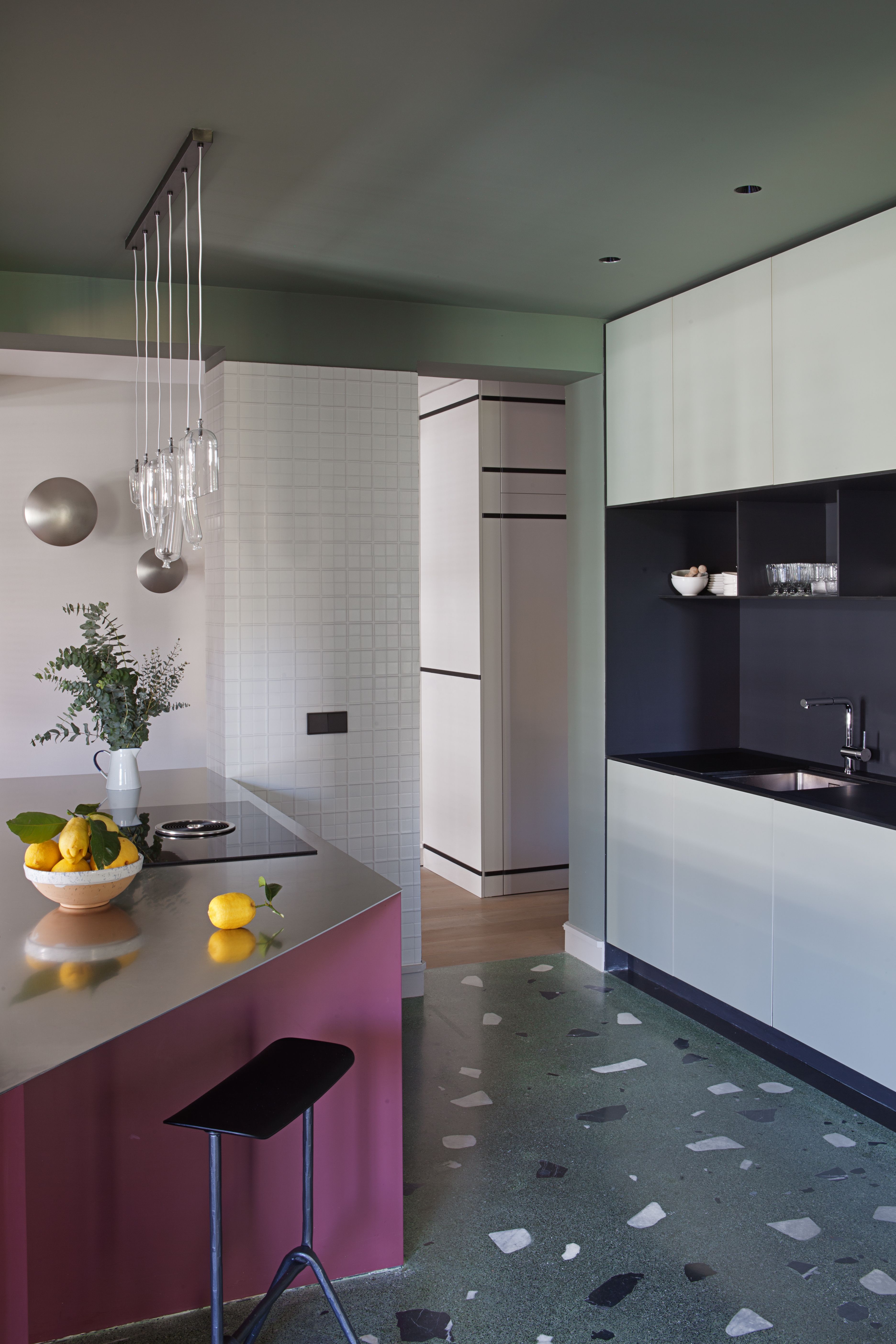 A kitchen with an angled top, a purple base and steel counter