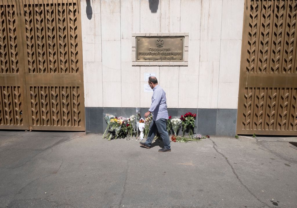 A man walks past flowers placed outside the Russian embassy in Tehran, Iran, to honor the victims of a shooting at the Crocus City Hall concert venue near Moscow, Russia