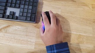 a hand resting on a slim black gaming mouse lit up