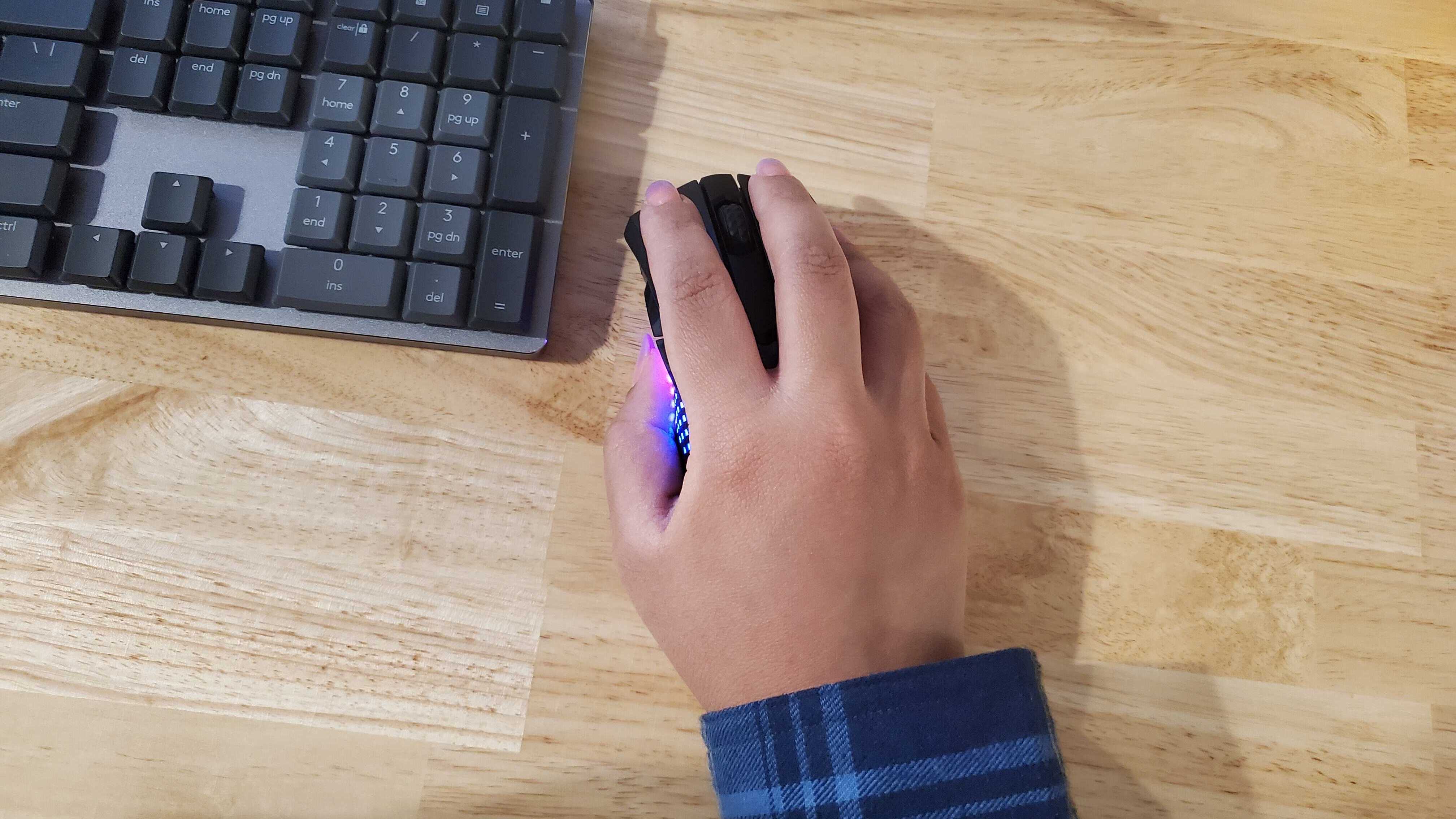 a hand resting on a slim black gaming mouse lit up