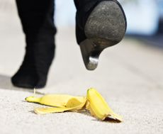 An unidentified female walker's foot in high-heeled boots is about to step on a dropped banana peel. A painful fall coming in 3, 2, 1...