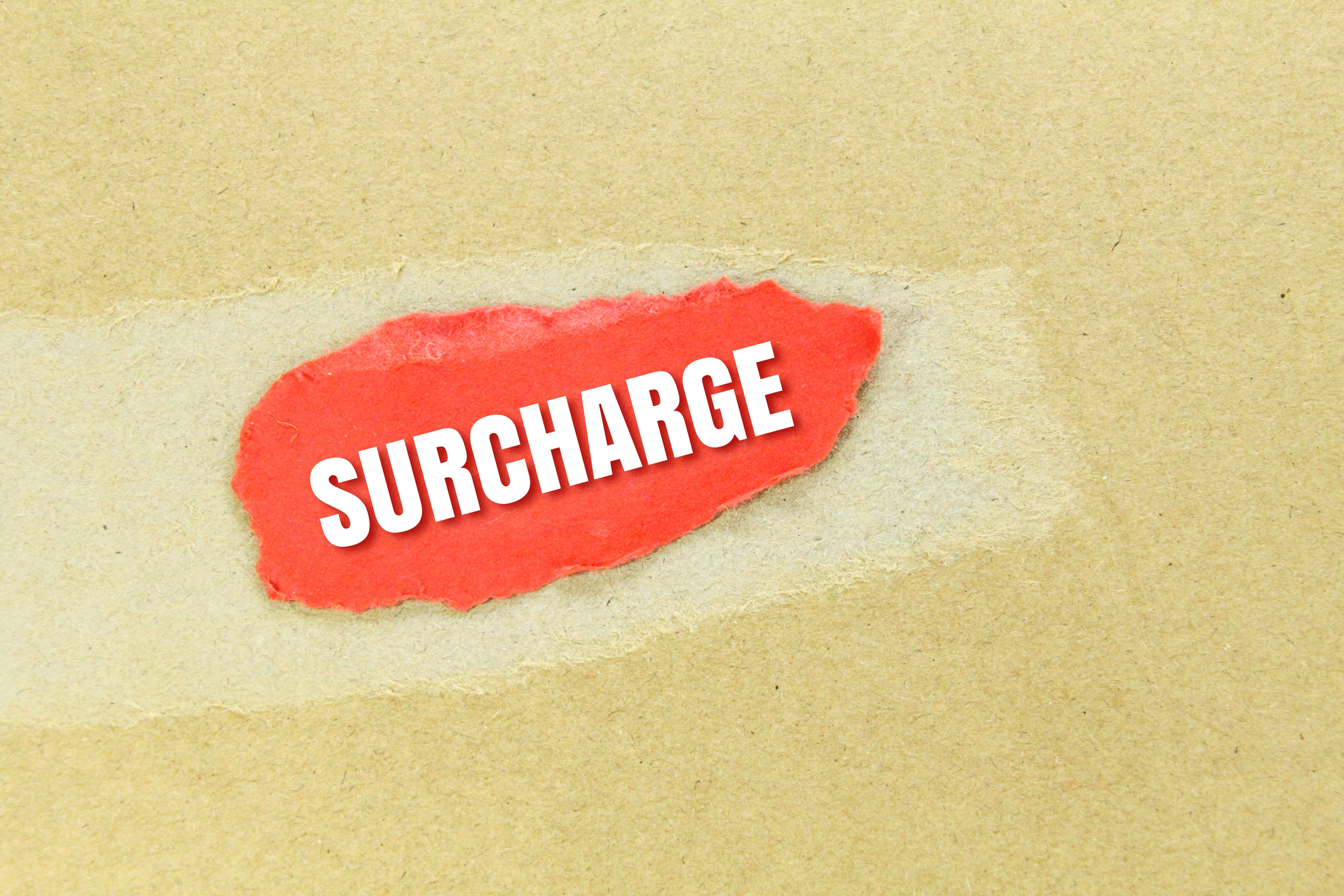 Colored torn paper with the word surcharge. an additional charge or payment