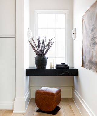 White laundry room with black honed soapstone table top and leather stool