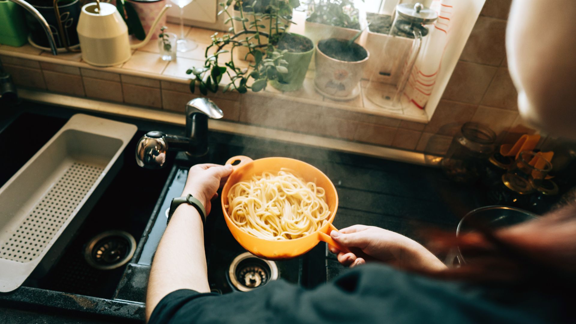 Person draining a pot of pasta