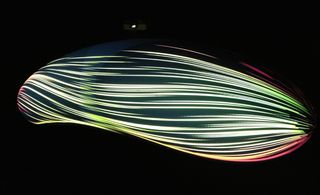 Black background, lines of colourful glowing lights in the shape of a car at speed