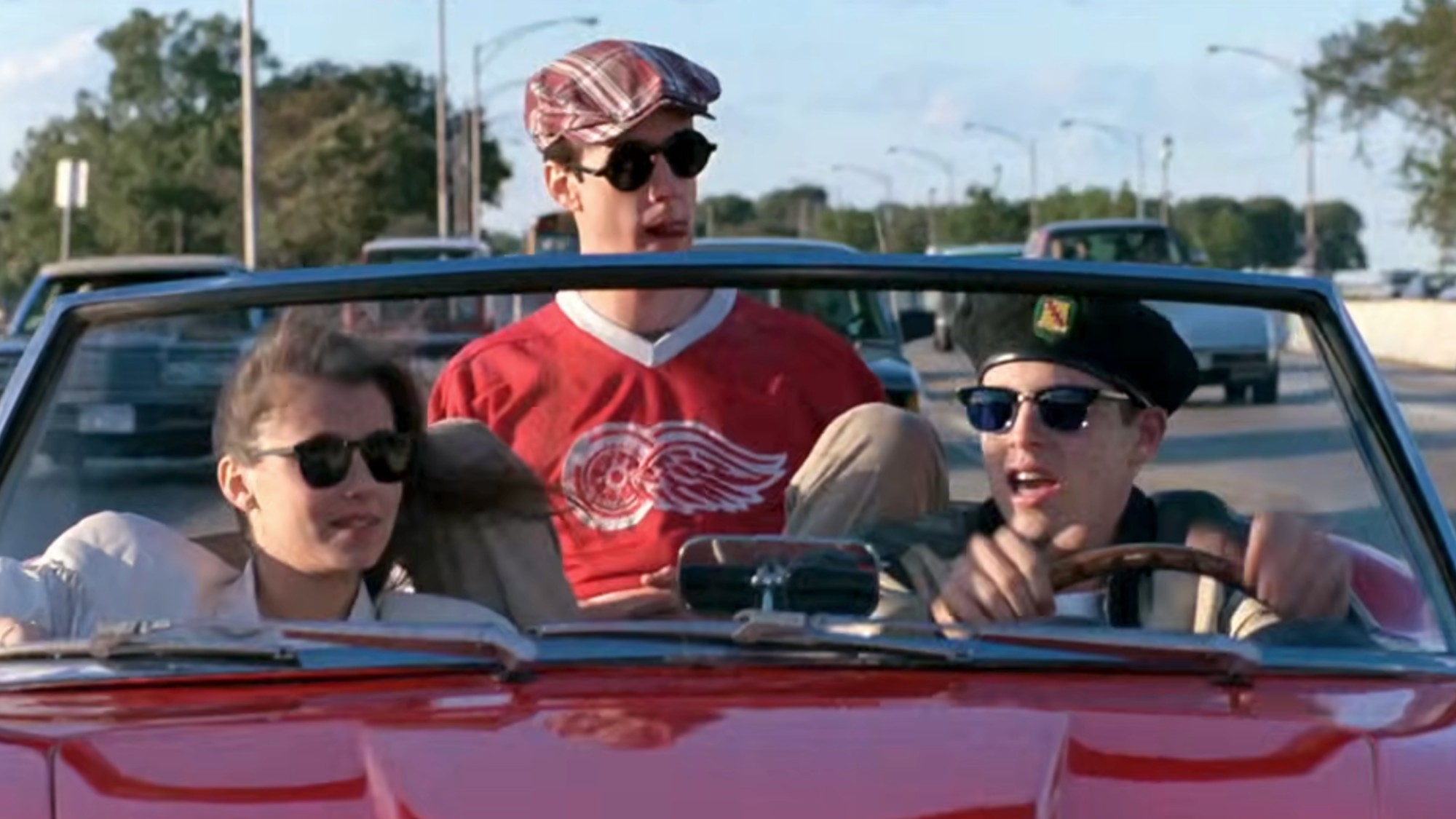 Matthew Broderick driving a red car with Mia Sara and Alan Ruck riding in the car in Ferris Buellers Day Off