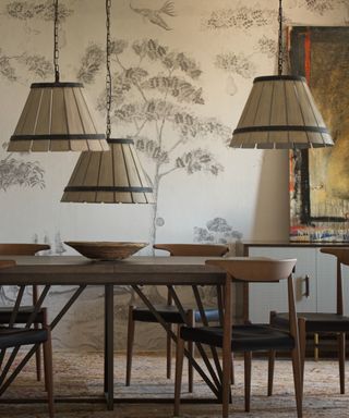 neutral dining room with retro table and chair, wooden pendant lights, wooden bowl, dried flower wallpaper on cream background, artwork on sideboard to the right