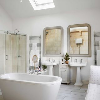 white bathroom with vaulted ceiling, double vanities and freestanding bath