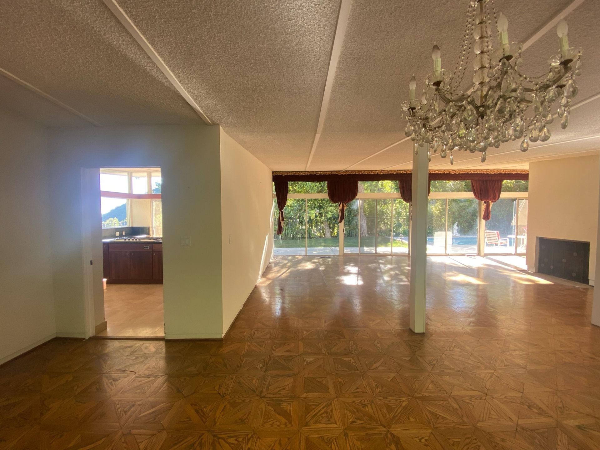 An open plan living room with large windows and parquet flooring