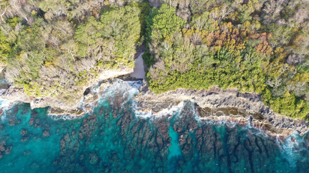 Waves crashing into a cliff from top down.