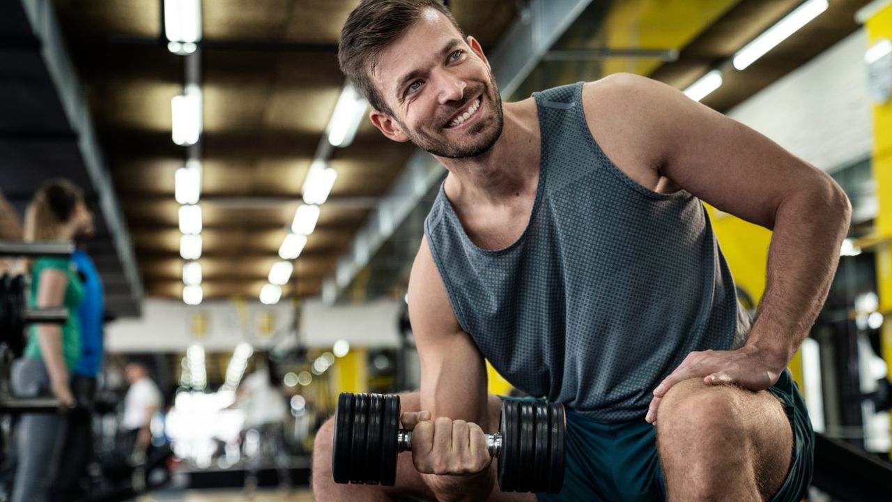 A man doing concentration bicep curls in the gym