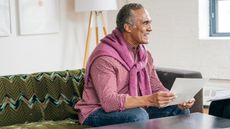 Smiling senior man on sofa holding a letter