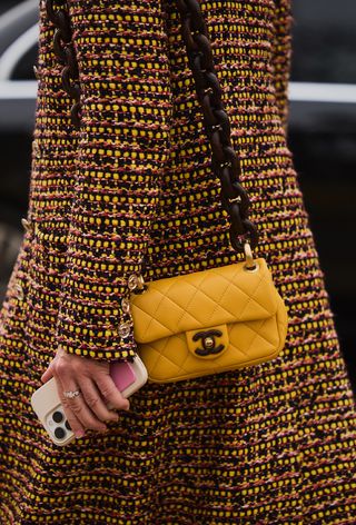 a street style photo of a woman wearing a tweed coat with a yellow chanel bag