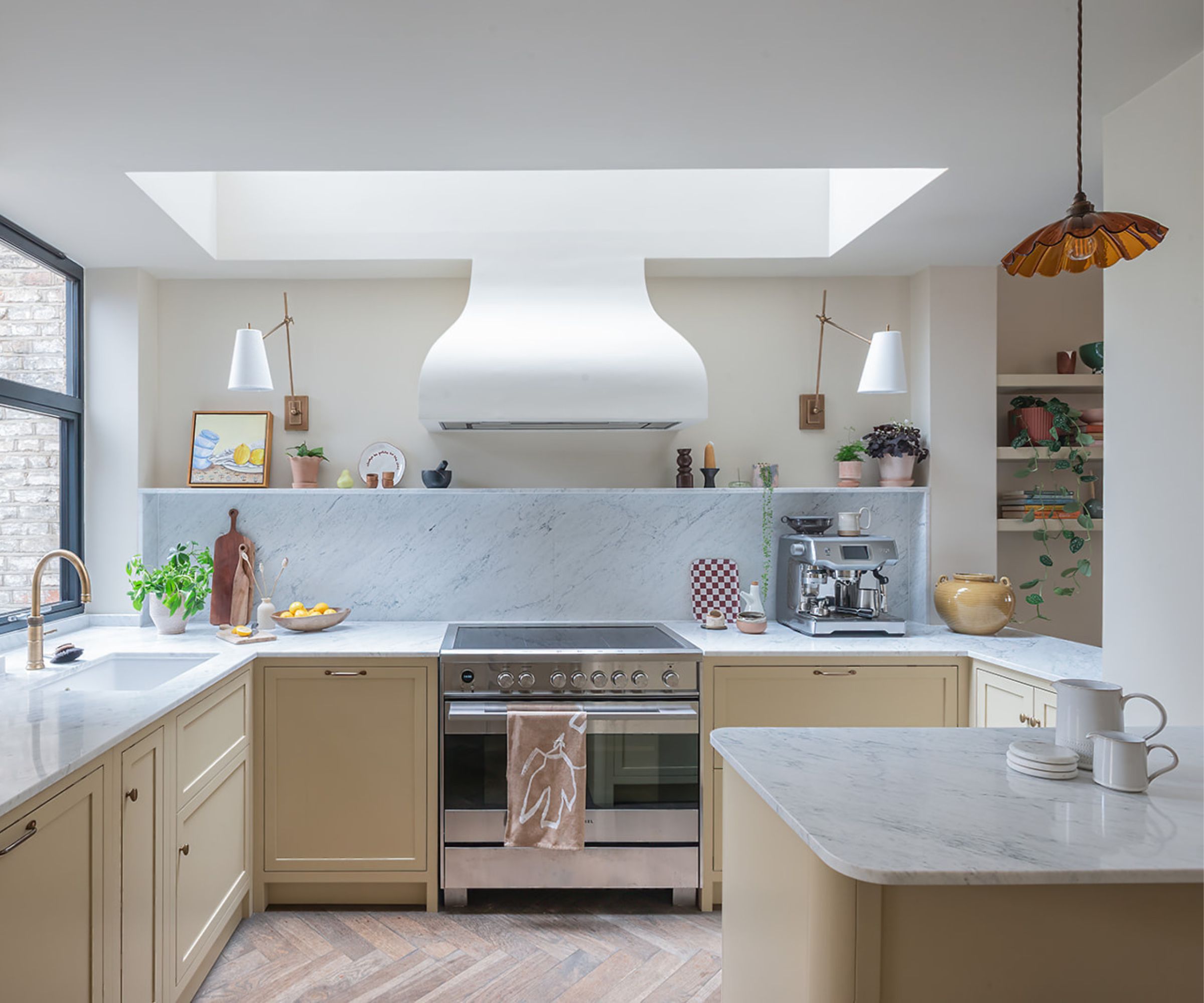 A small U-shaped kitchen with a peninsula island, beige cabinets, cream walls, and marble countertops
