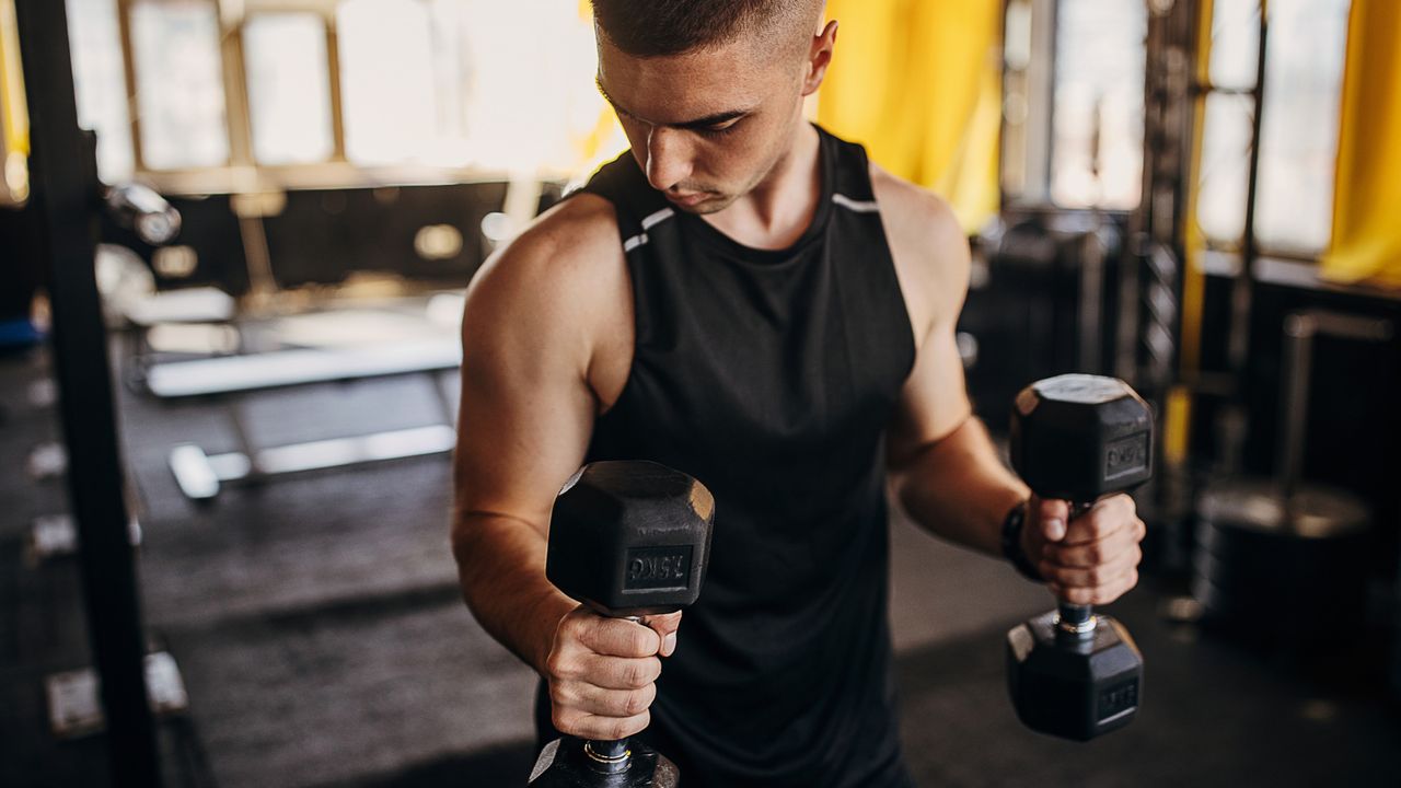 A man performing a dumbbell hammer curl in a gym