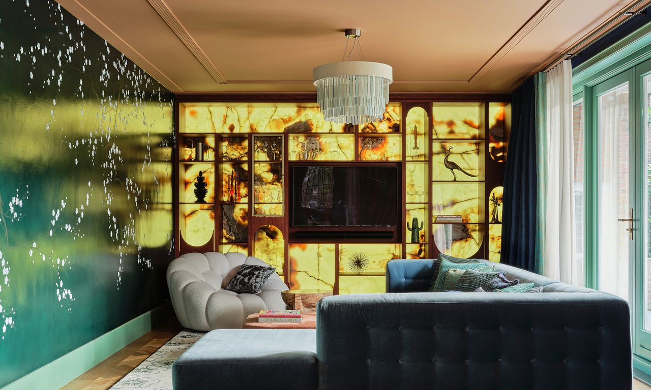 Living area with backlit cabinetry, green mural wall, teal corner sofa and pale grey armchair