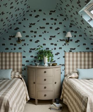 bedroom with twin beds with gingham headboards and bedding, mid-blue patterned wallpaper with sheep