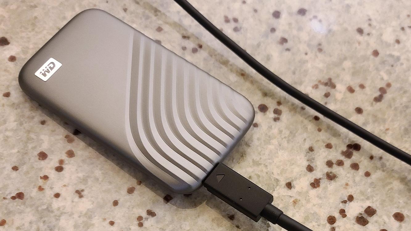 WD My Passport SSD on table connected to wire