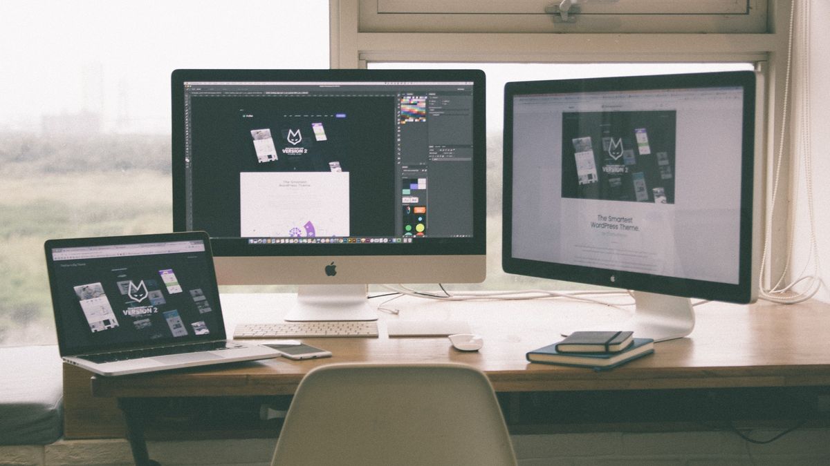 Mac laptop and monitors on a desk showing website development