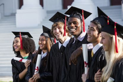 A group of young people in cap and gown celebrating after graduation.
