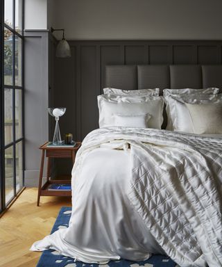 A bedroom with Crittall-style black framed window decor and bed with cream Mulberry Silk linen