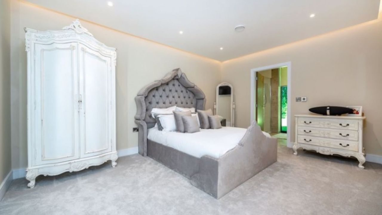 The master bedroom with grey bed frame and a Victorian cabinet