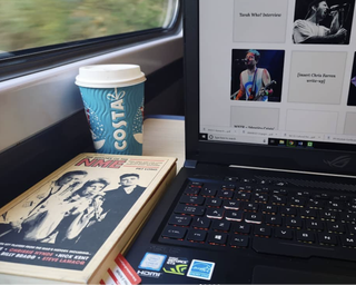 Back to school supplies: ; an Asus laptop with a takeaway coffee cup and NME book on a train table