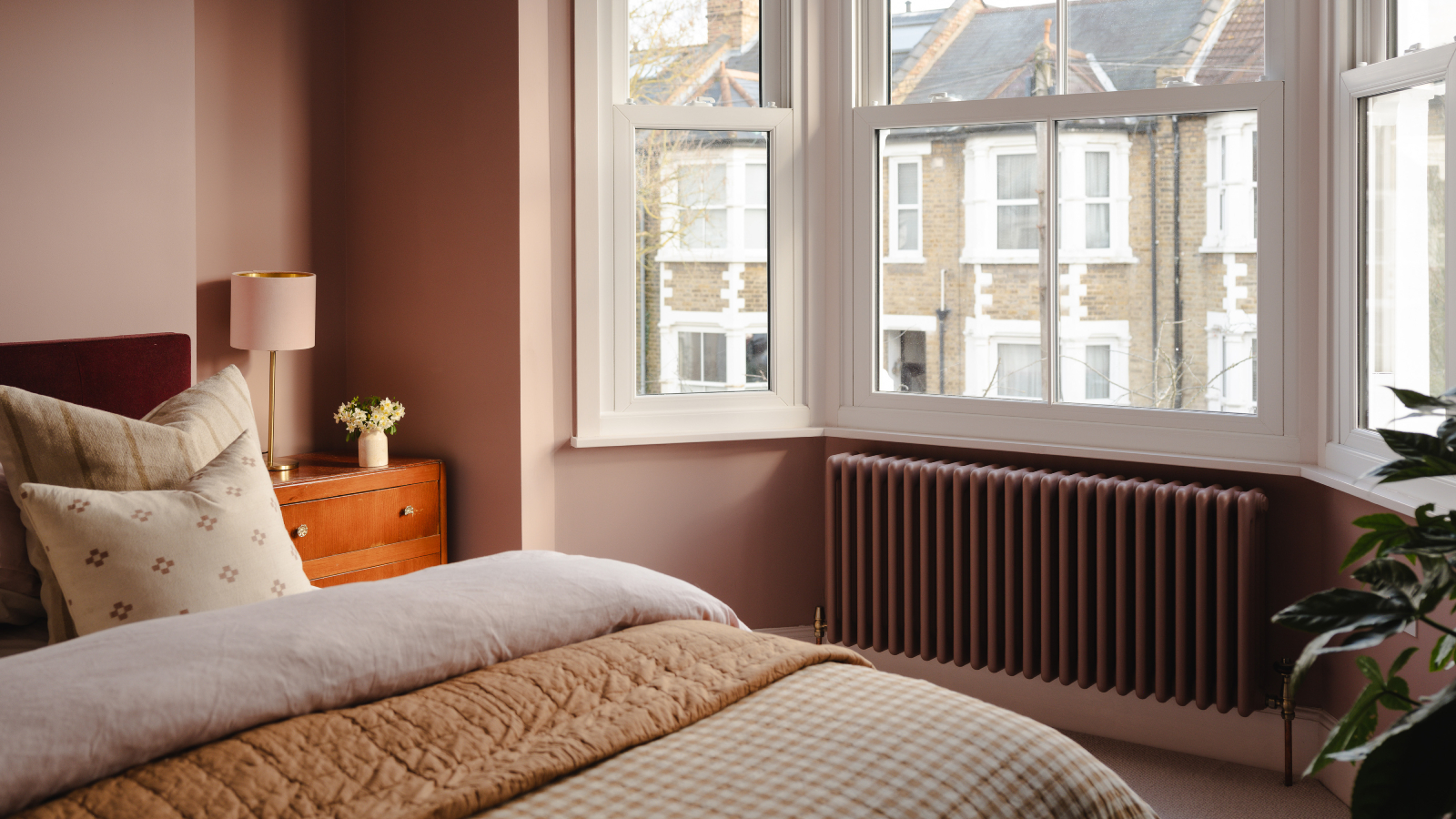bedroom with column radiator in dark dusky pink colour in bay window