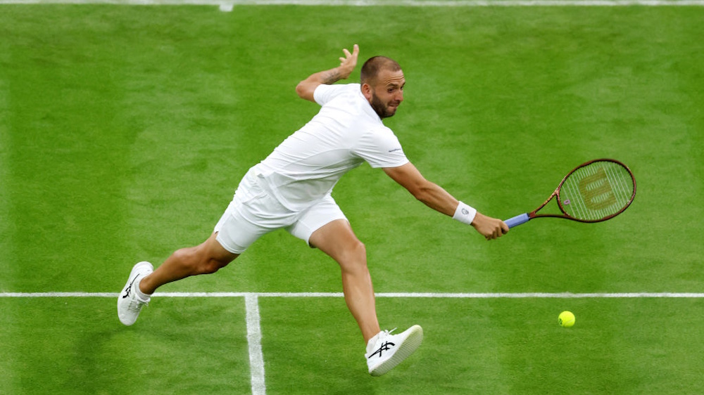 Daniel Evans stretching for a backhand during a match at Wimbledon in 2023.