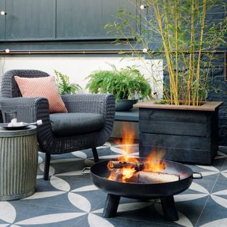 Patio with patterned tiles and black painted walls and a firepit