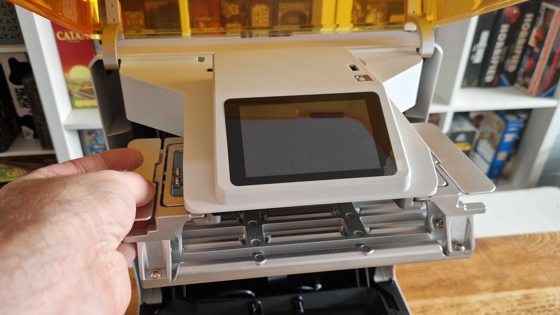 A hand reaches out to hold the Creality Halot-X1 twisting build plate