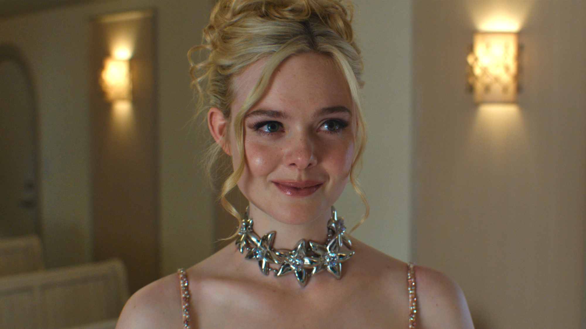 Elle Fanning smiling with up do and a chunky silver necklace in Margo's Got Money Troubles episode "Flamingos"