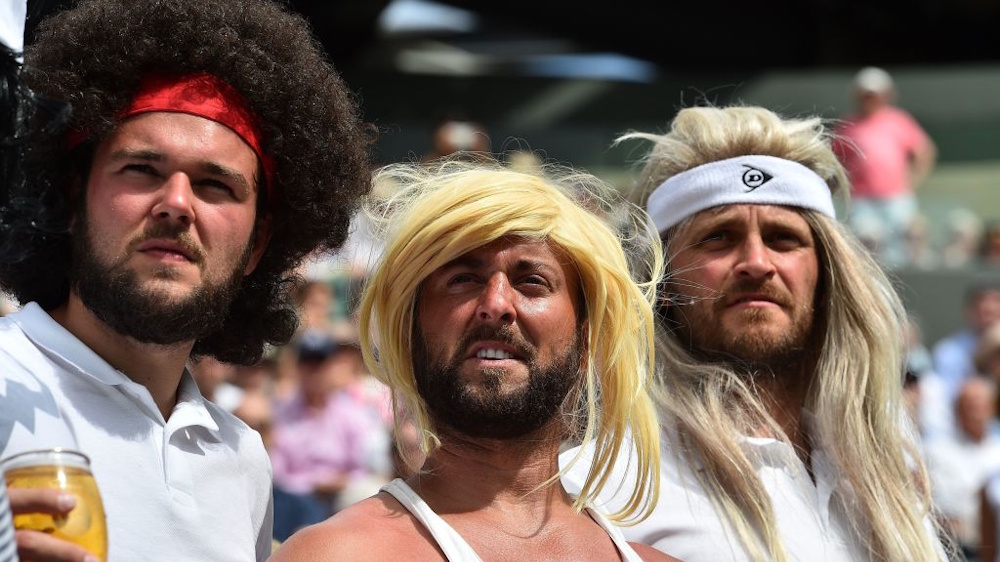 Tennis fans wearing wigs resembling legendary players at Wimbledon.