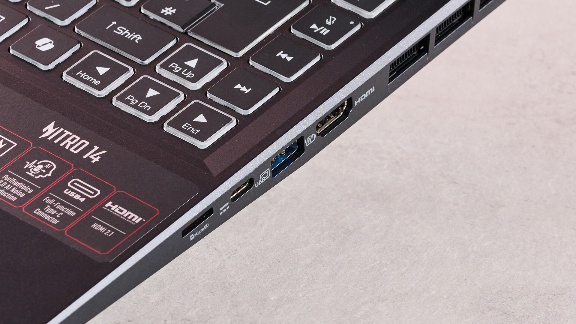 The Acer Nitro 14 compact gaming laptop photographed on a coral background.