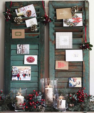 A set of two wooden window shutters which have been used to display Christmas card decor