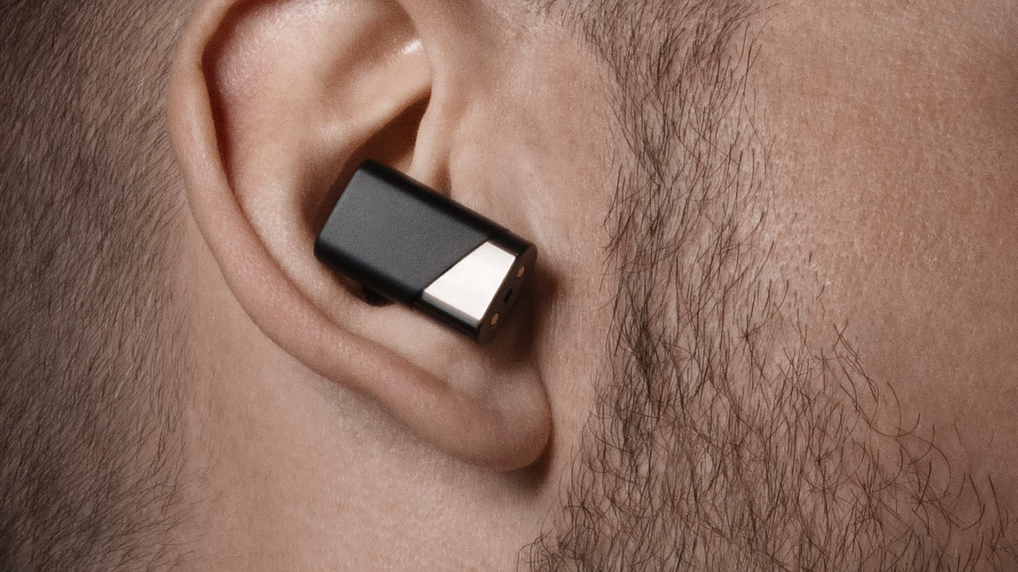 A close-up of the Status Audio Pro X earbuds in a man's ear
