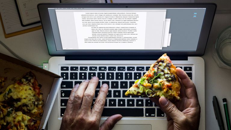 Person eats pizza late at night as they work on a laptop